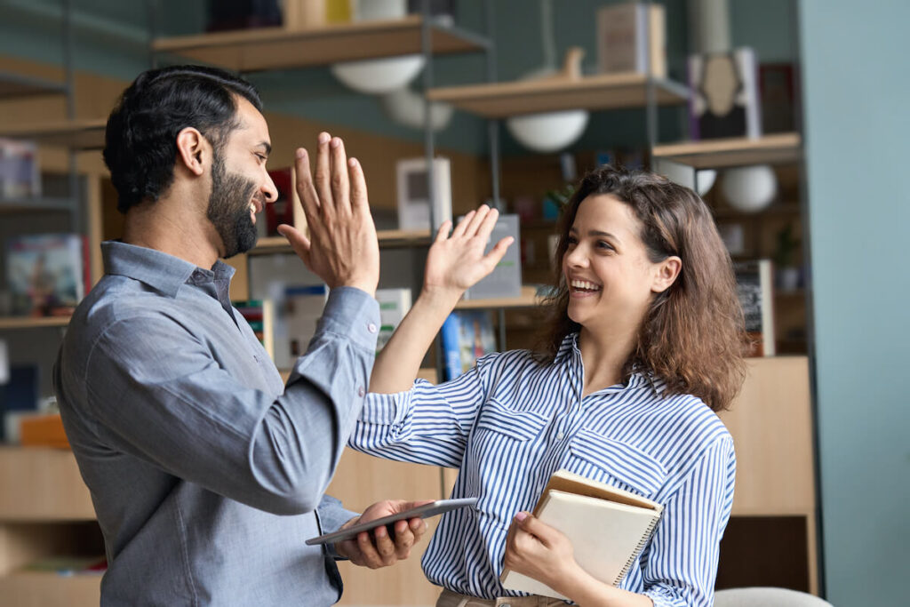 Two happy engaged employees given each other a high five